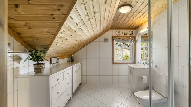 Badet i loftsetasjen har flislagt gulv med gulvvarme og dusjkabinett.