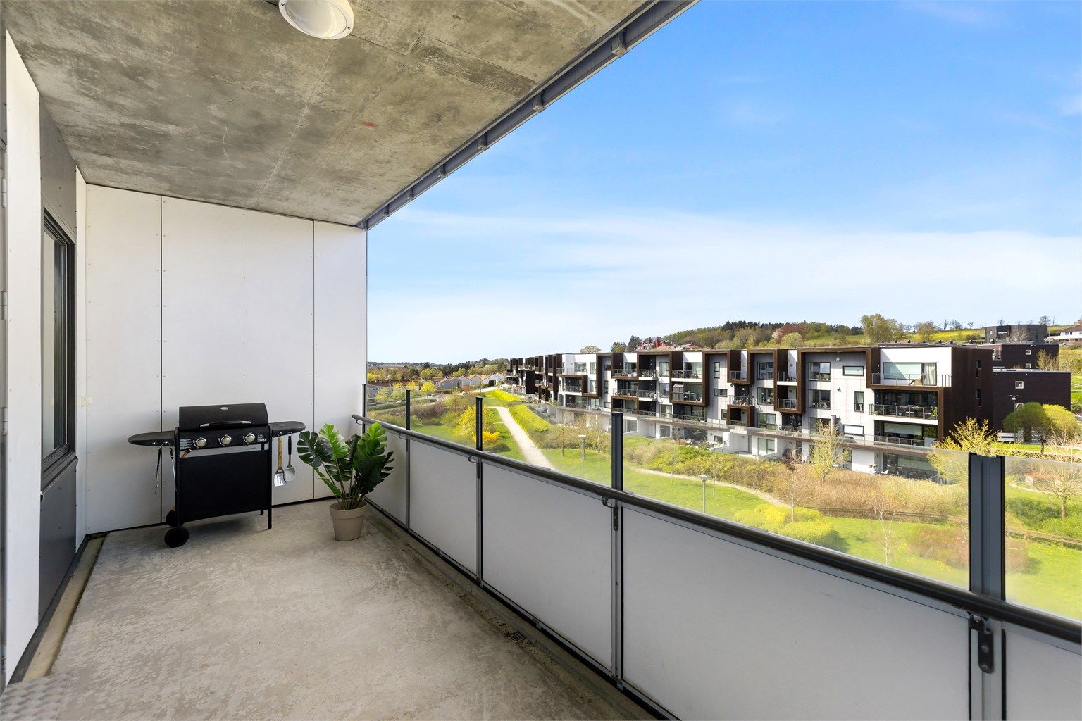 Den romslige balkongen på 13 m² gir rikelig med plass for en sittegruppe og har utsikt over grønne fellesområder.