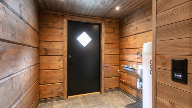 Praktisk vaskerom med egen utgang, flislagt gulv med gulvvarme og utslagsvask i stål. Varmtvannsberederen er plassert her.