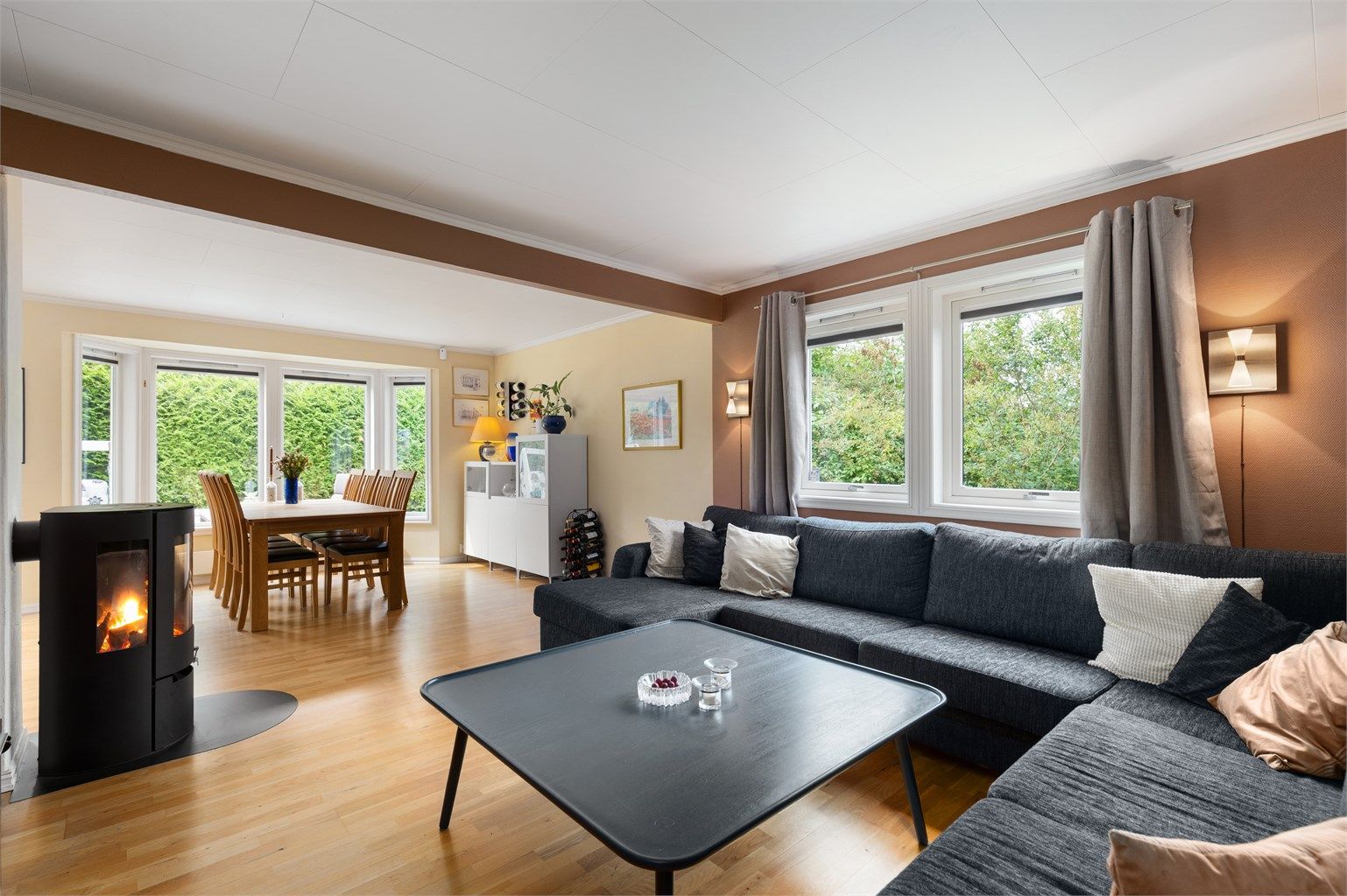 Det er god plass til både en stor sofagruppe med tilhørende møblement og en romslig spiseavdeling, noe som gjør stuen anvendelig til både hverdag og sosiale sammenkomster.