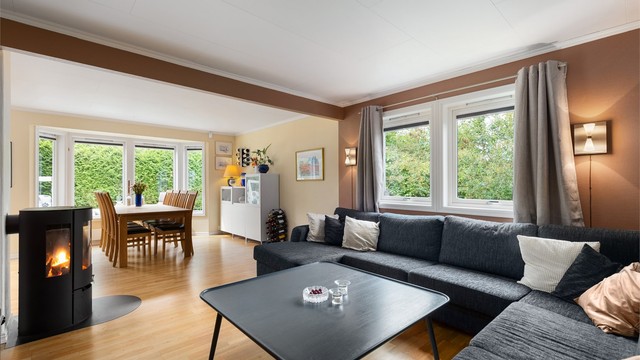 Det er god plass til både en stor sofagruppe med tilhørende møblement og en romslig spiseavdeling, noe som gjør stuen anvendelig til både hverdag og sosiale sammenkomster.
