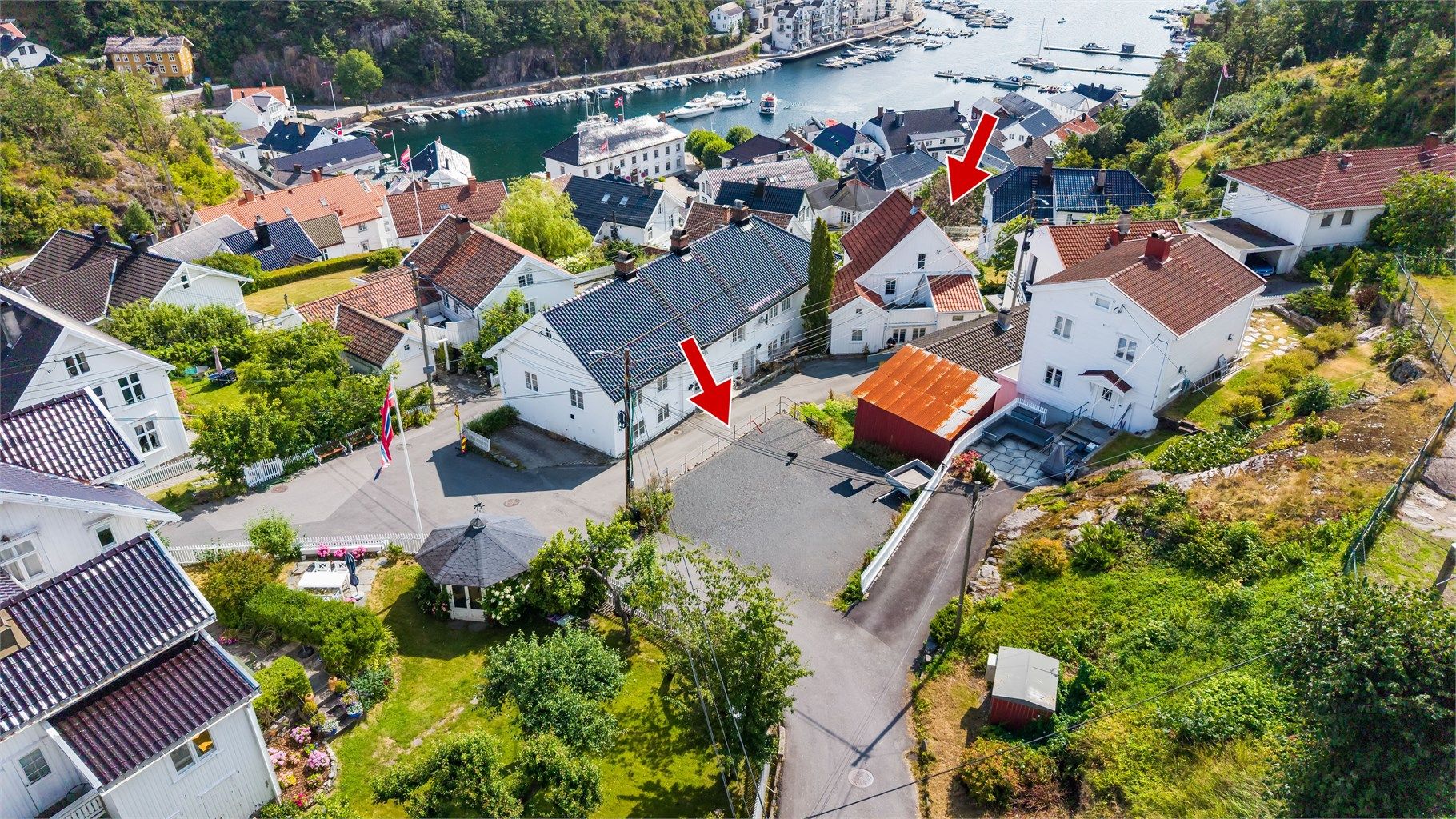 Eiendommen inkluderer enebolig, uthus og stor, gruset p-plass som er synlig i bildet.