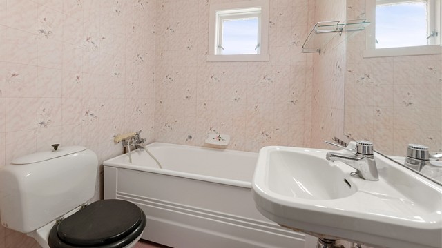 Badet i første etasje er av eldre dato og utstyrt med badekar, toalett og servant