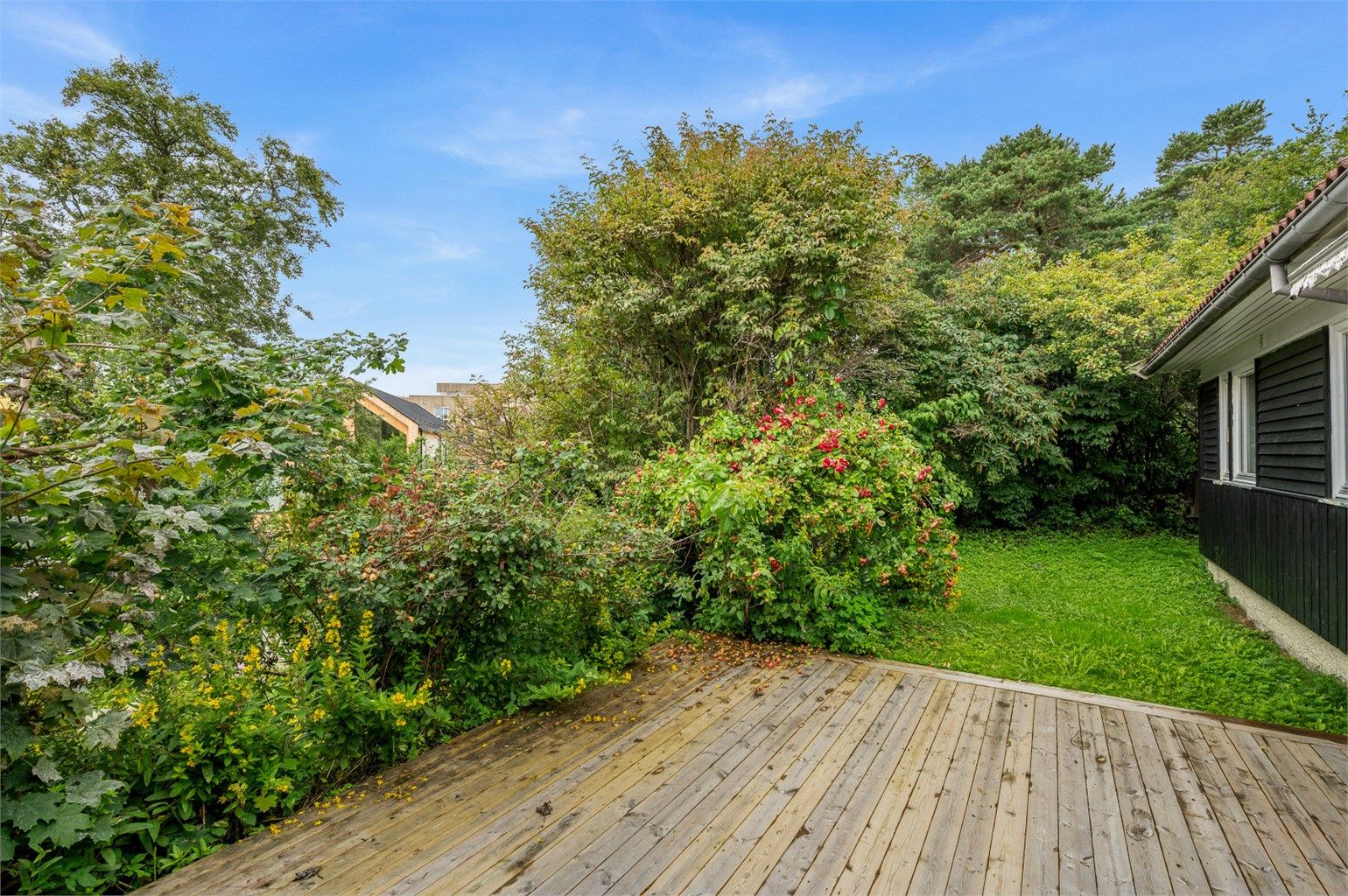 Fra stuen er det direkte utgang til terrasse og videre til den frodige hagen. Terrassen gir en hyggelig og skjermet uteplass – selger opplyser om solforhold fra ca. kl. 09 til 21 på sommerstid.