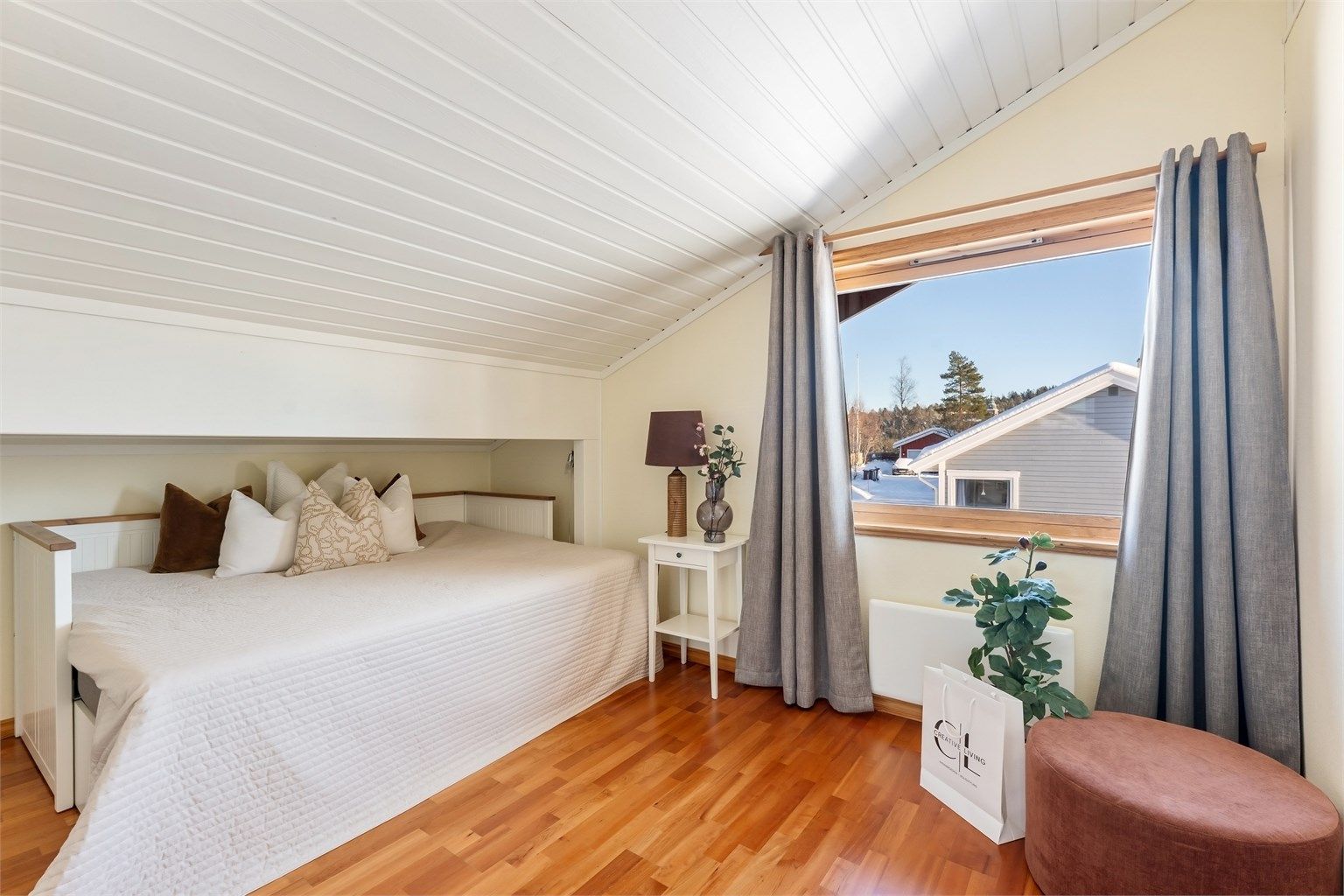 Det ene av to soverom i loftetasjen, med laminatgulv og panel i taket.