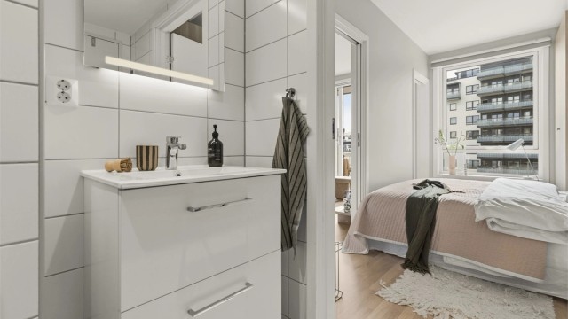Badet består av skap med glatte fronter, servant med armatur, speil på vegg, klosett og dusj på gulv med armatur og dusjvegger. Adkomst til badet fra soverommet