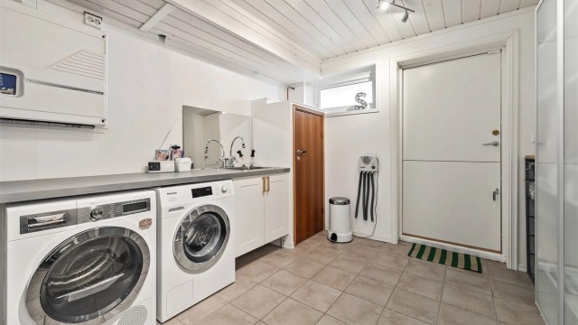 Praktisk vaskerom fra ca. 2008 med flislagt gulv, benkeplate med skyllekum og sentralstøvsuger. Ikke bruksendret/omsøkt rommet.