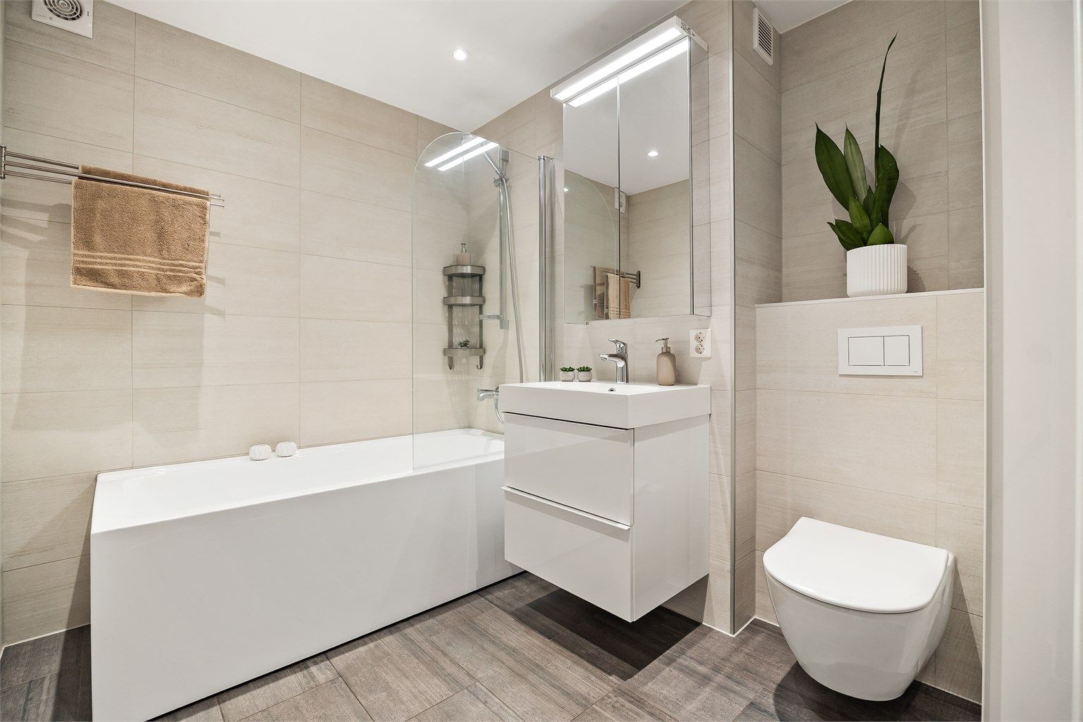 Badet er fra 2022 og har flislagt gulv med gulvvarme, badekar og vegghengt toalett.