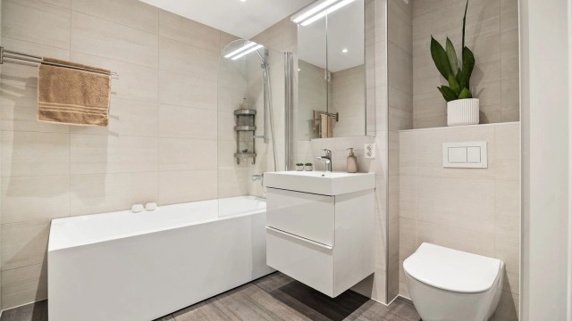 Badet er fra 2022 og har flislagt gulv med gulvvarme, badekar og vegghengt toalett.