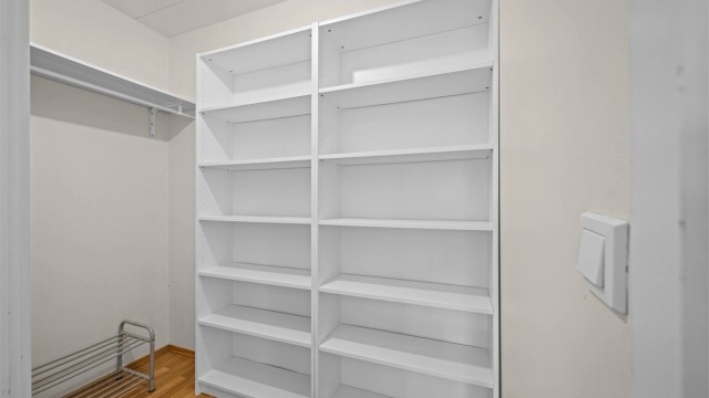 Innvendig bod innredet med praktiske hylleløsninger gir verdifull lagringsplass i leiligheten.