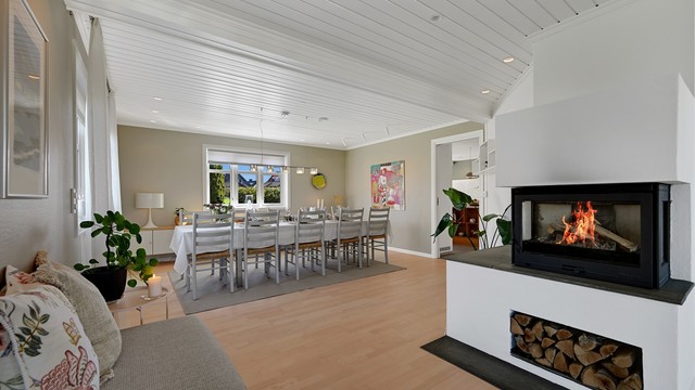 Peisen med innsats skaper en lun atmosfære og fungerer som en naturlig romdeler mot spisestuen.