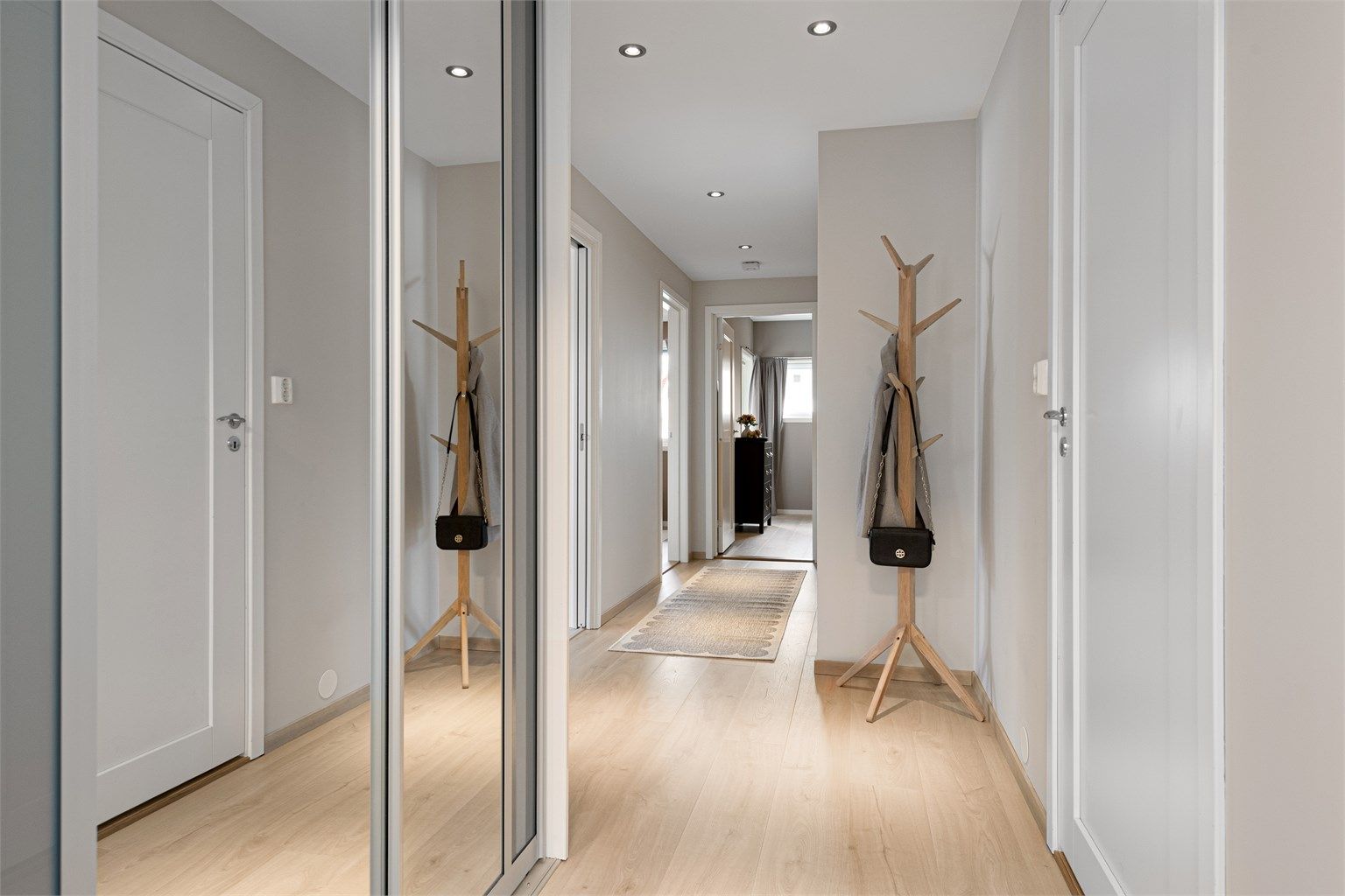 Entré med skyvedørsgarderobe med speilfronter og innfelte spotter i himling.
