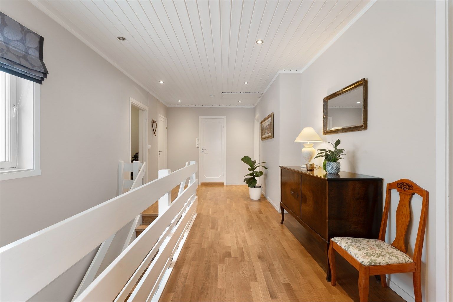 Fra den sentrale gangen med parkettgulv og downlights i himling, åpner boligen seg opp.