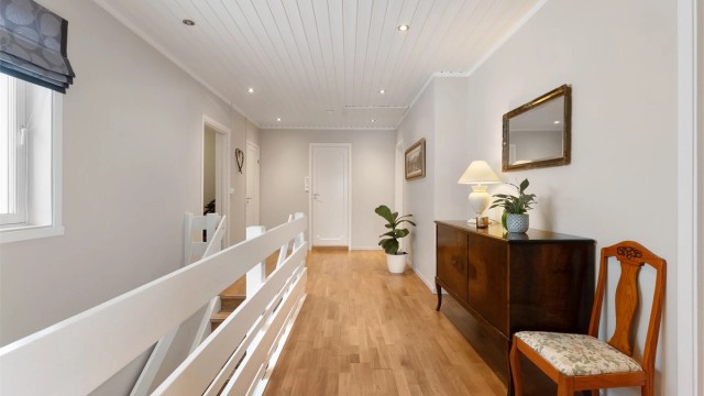 Fra den sentrale gangen med parkettgulv og downlights i himling, åpner boligen seg opp.