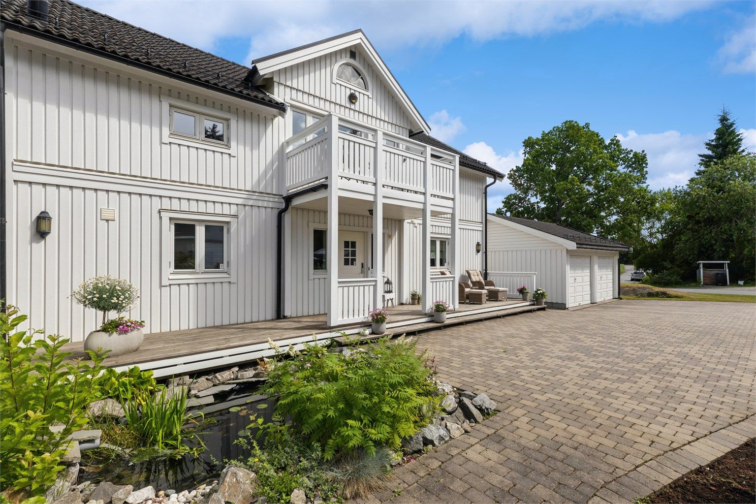 Boligen har en klassisk arkitektur og fremstår som svært godt vedlikeholdt. Legg også merke til den sjarmerende karpedammen som bidrar til et hyggelig uterom.