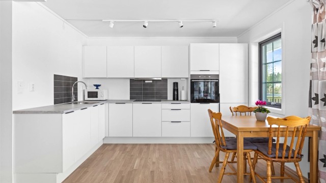 Kjøkkeninnredningen har glatte fronter og en slitesterk benkeplate med laminert overflate.
