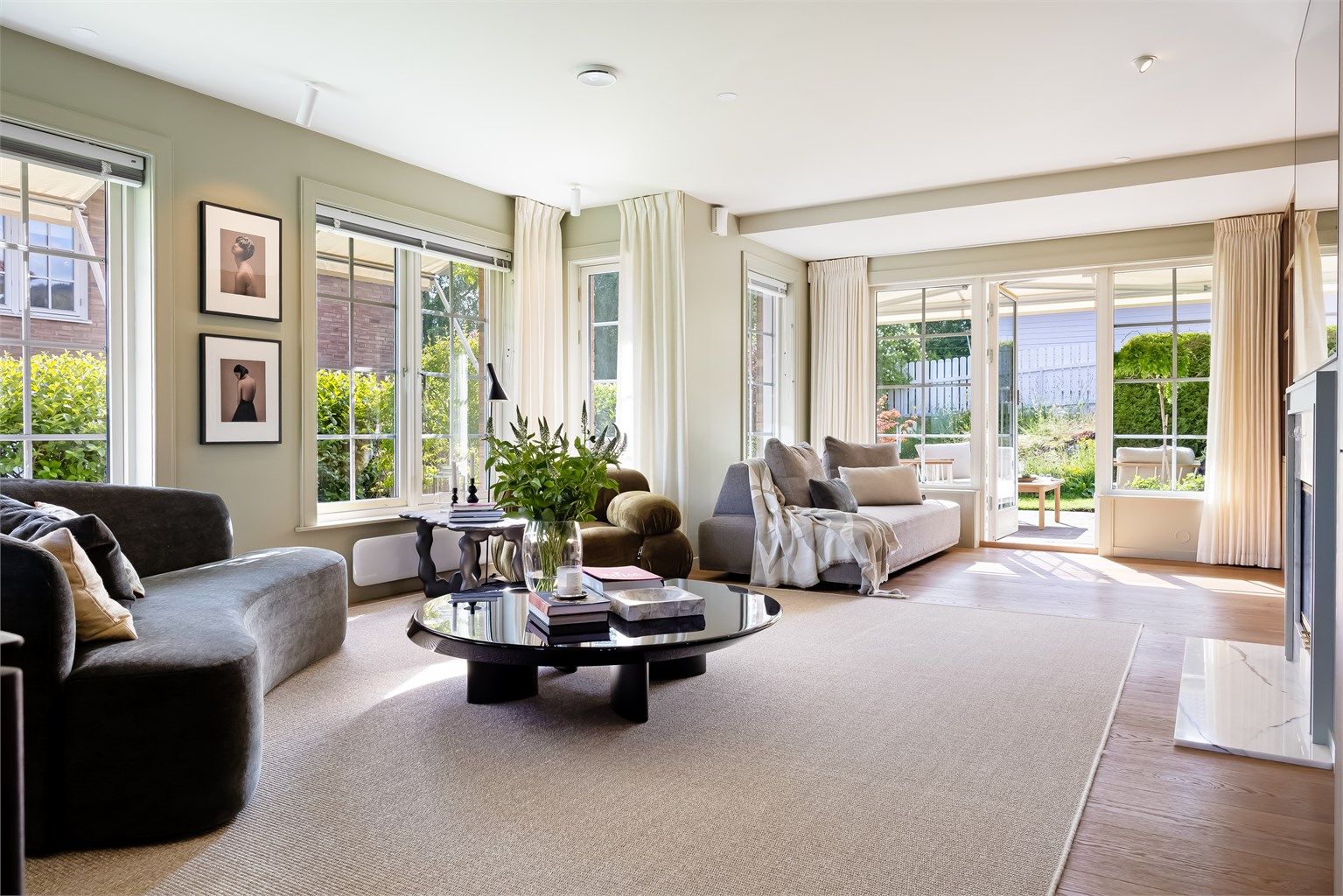 Romslig stue med store vindusflater som slipper inn rikelig med naturlig lys og gir utsyn over hyggelig grøntområde.