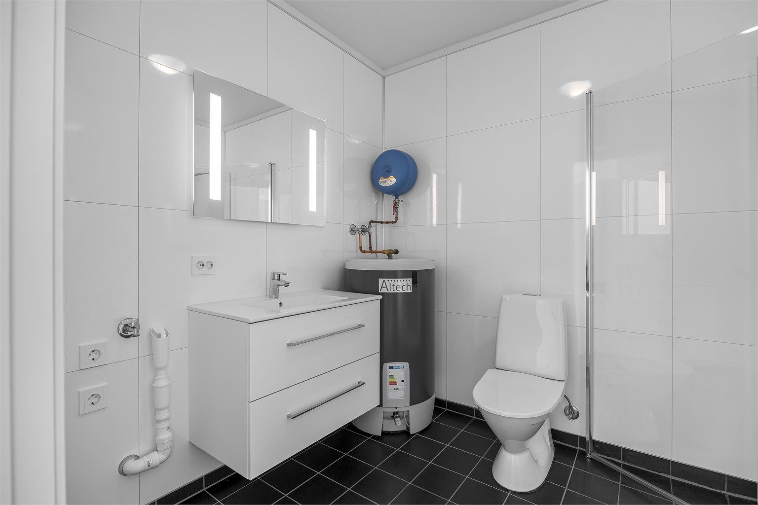 Badet har flislagt gulv, baderomsplater på veggene og opplegg for vaskemaskin.
