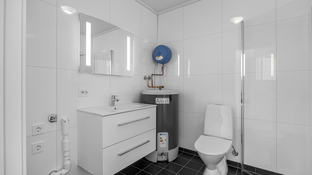 Badet har flislagt gulv, baderomsplater på veggene og opplegg for vaskemaskin.