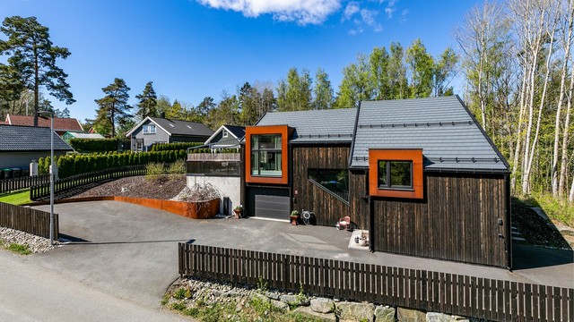 Stakittgjerde rundt gårdsplassen og del av hagen er beiset i samme nyanse som boligens kledning.