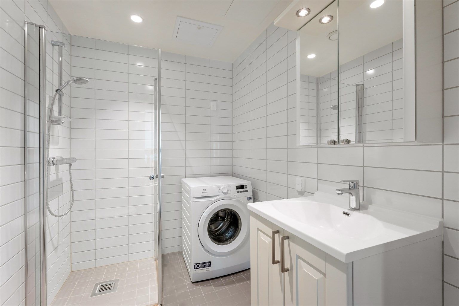 Her er det dusjhjørne med innfellbare glassdører og opplegg for vaskemaskin.