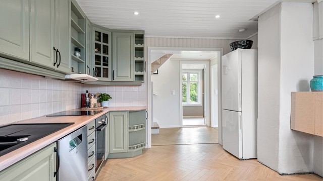 Downlights i taket gir god arbeidsbelysning, og det er fliser mellom benk og overskap.