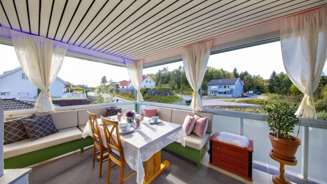 Fra stuen er det utgang til en innglasset og overbygget veranda. Vindusglassene kan skyves helt til siden om ønskelig.