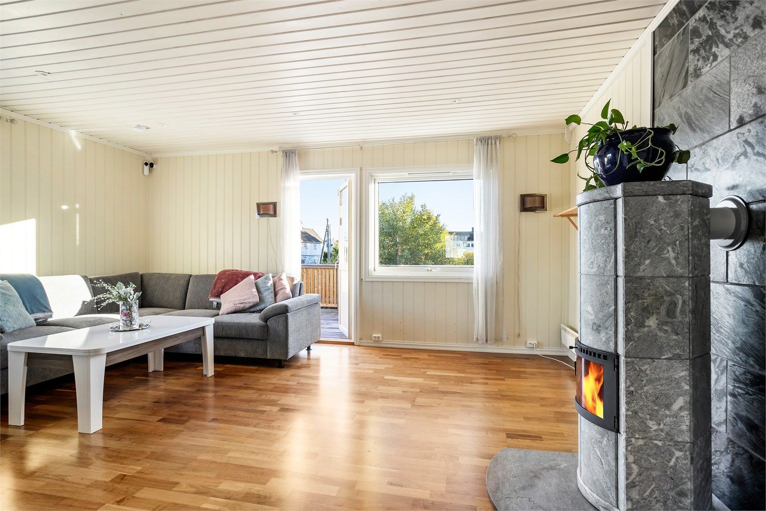 Lys selveierleilighet i firemannsbolig med sydvendt veranda og peisovn i stuen. 