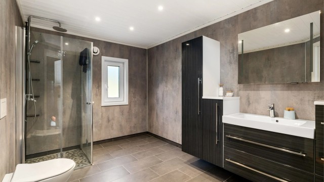 STILRENT: Grå matchende fliser på gulv og våtromsplater på vegger - baderomsinnredningen er fra Lind Bad.