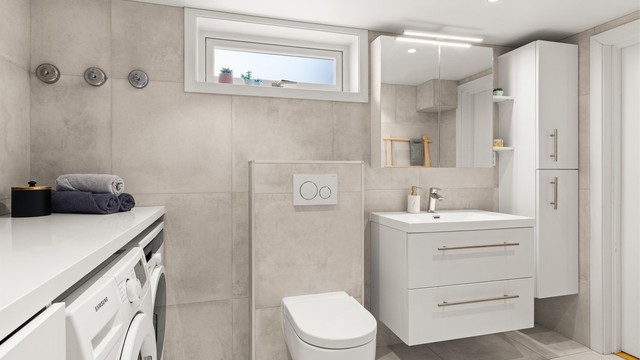 Innredningen inkluderer vegghengt servantmøbel, speilskap med belysning og ekstra høyskap for oppbevaring.