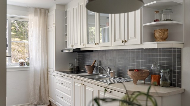 Stikkontakter og belysning mellom benk og overskap, samt mørke mosaikkfliser