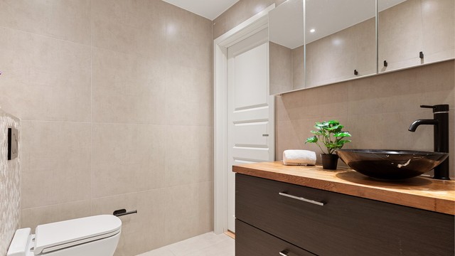 Bad med moderne innredning, vegghengt toalett og downlights i taket.
