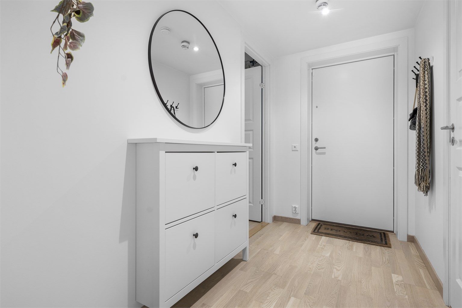 En lys entré med gjennomgående parkett ønsker velkommen inn.