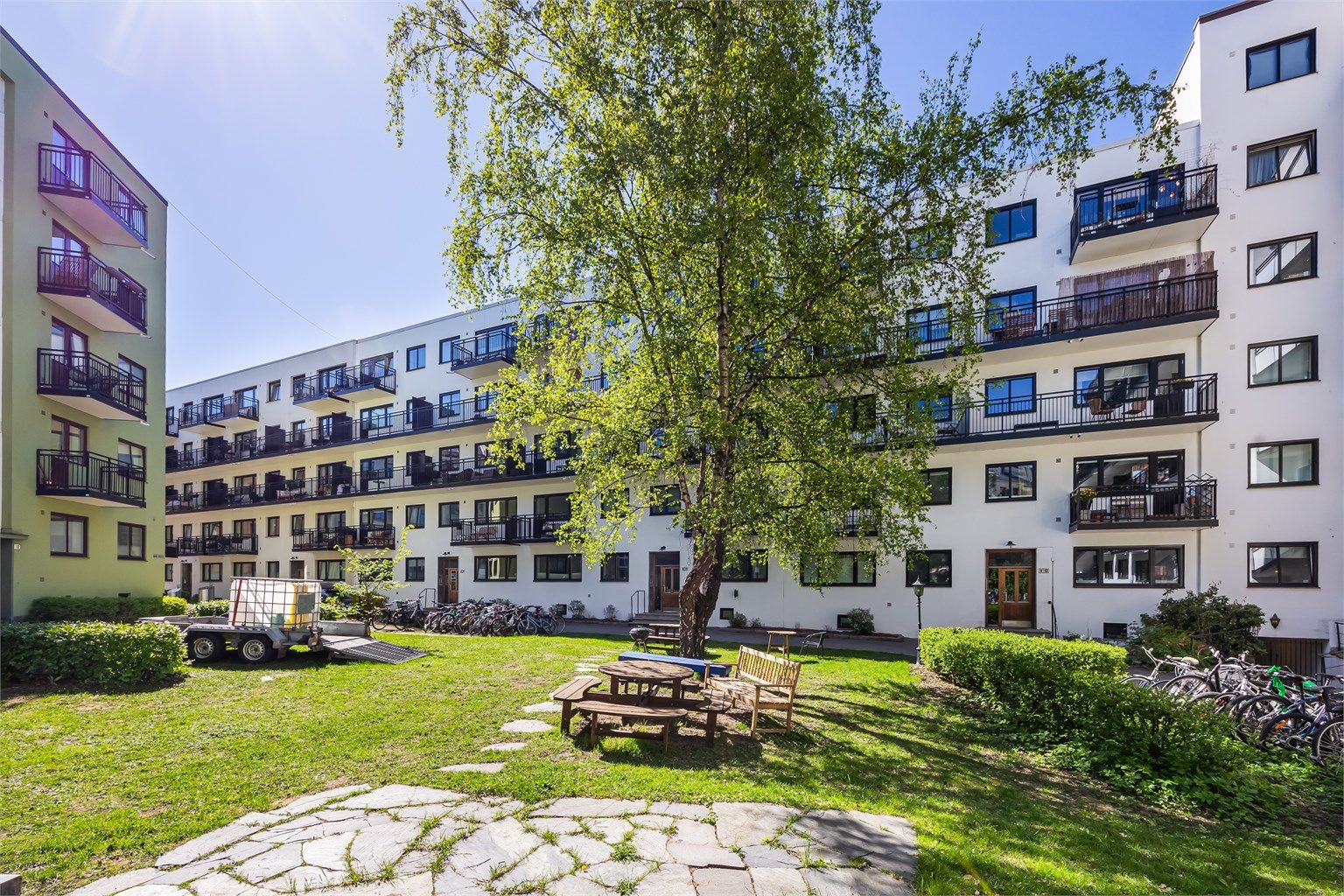 Bakgården er pent opparbeidet med plen, diverse beplantning, trær og sittegrupper. 