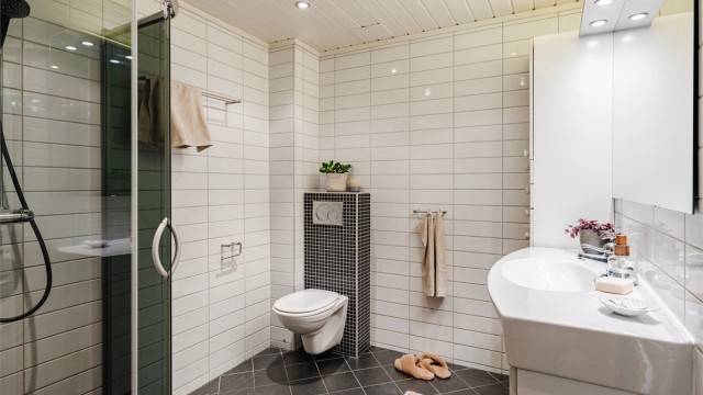 Et pent, flislagt baderom med varmekabler, downlights i himling og opplegg for vaskemaskin og tørketrommel i nisje