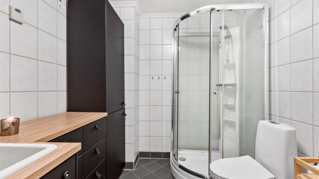 Badet er innredet med servant, toalett og et praktisk dusjkabinett.