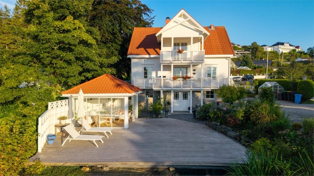 Fasade, hagestue og stor terrasseplatting mot vest