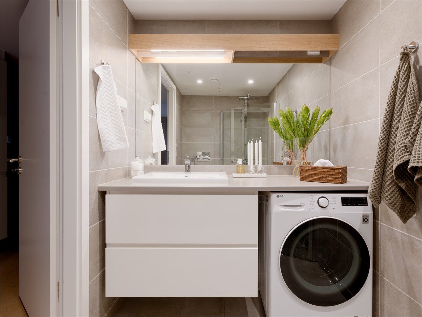 Baderomsinnredningen består av heldekkende benk med nedsenket servant og ett-greps armatur, speil over servant samt vegghengte baderomsskuffer med gode oppbevaringsmuligheter.