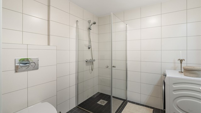 Dusjhjørne med innfellbare glassdører og vegghengt toalett.