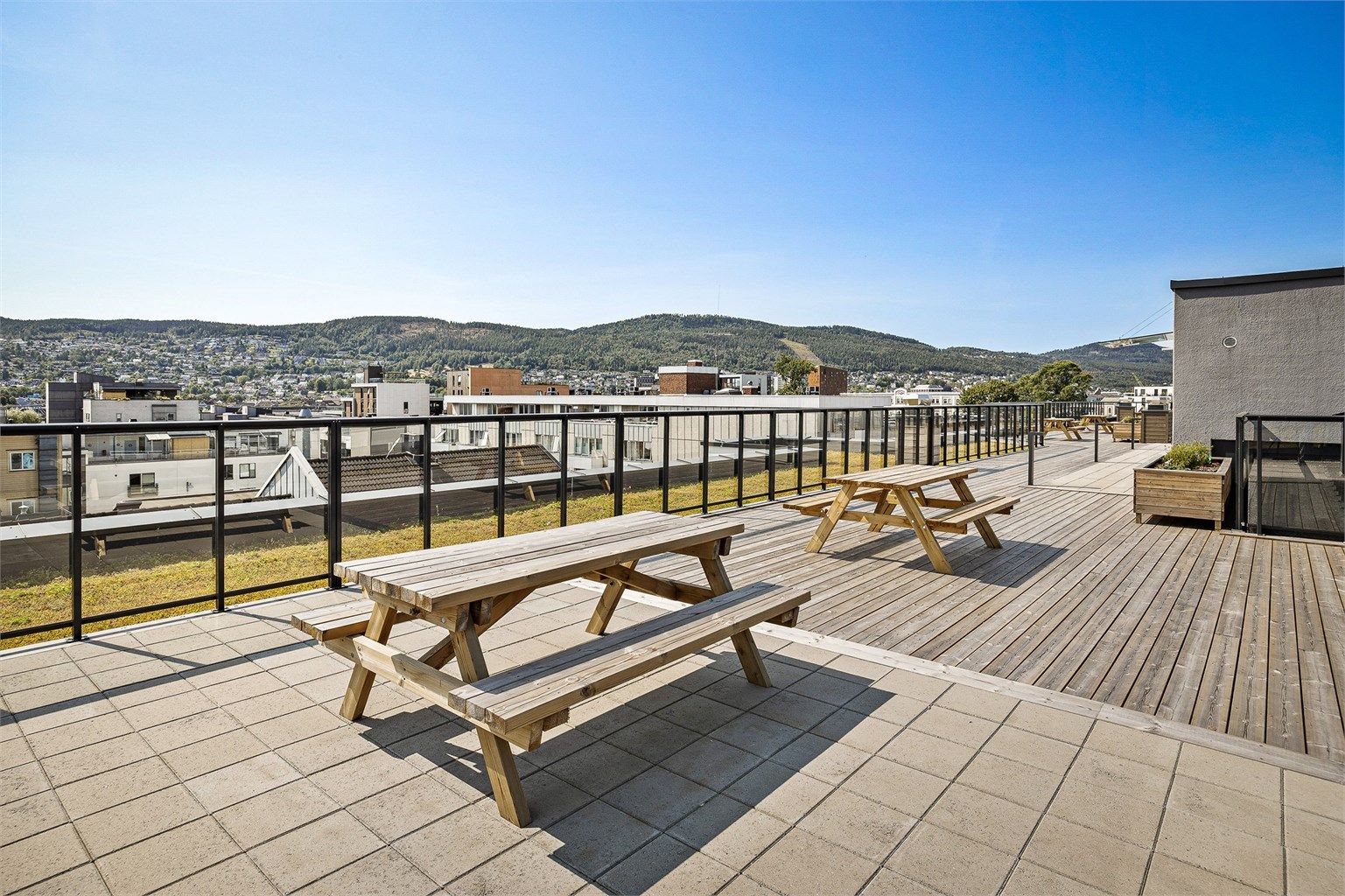 Beboere har tilgang til en romslig felles takterrasse med sittebenker - Sommerbilde fra tidligere annonse.