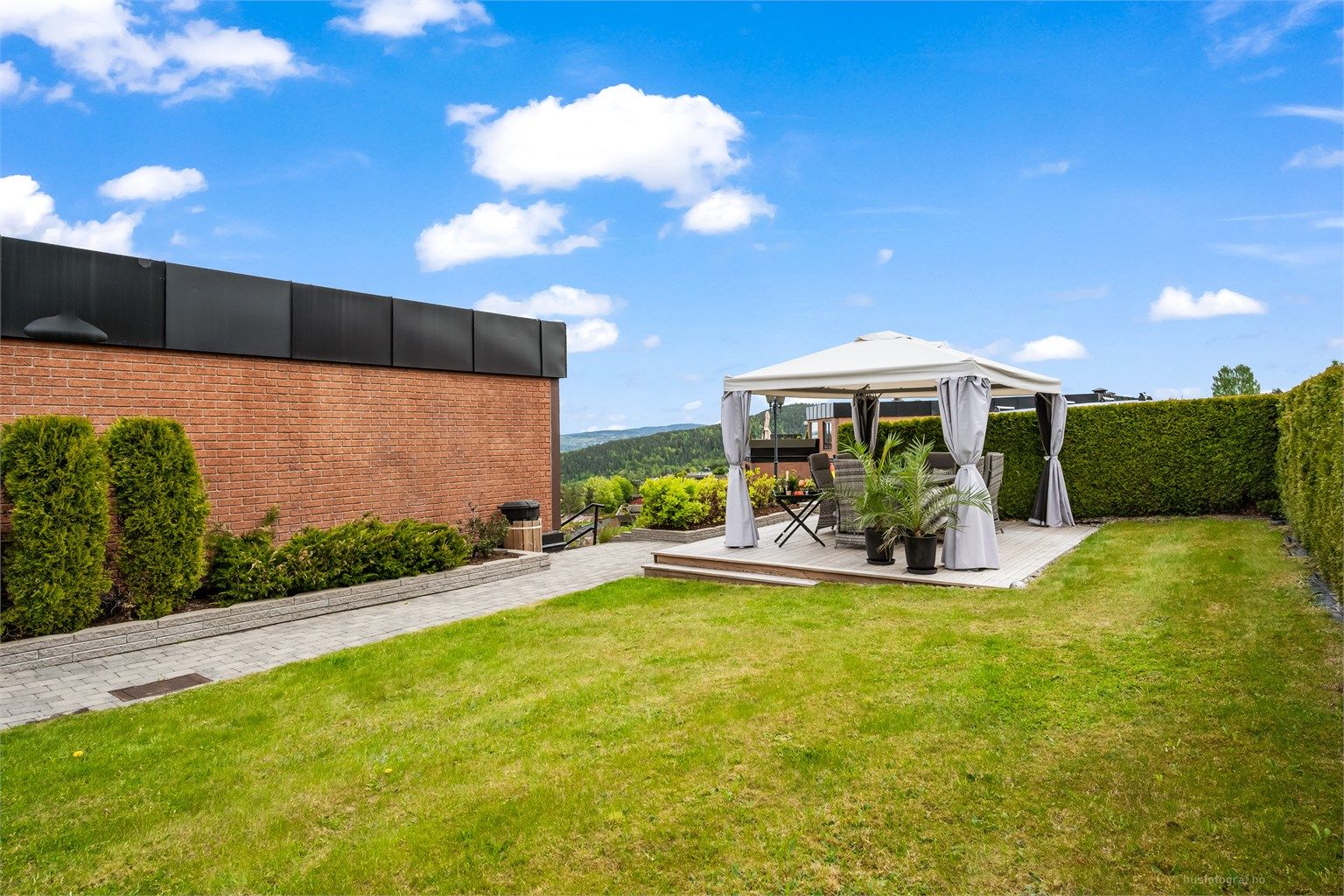 Fellesarealet er pent opparbeidet med nydelige beplantninger og platting med pergola.