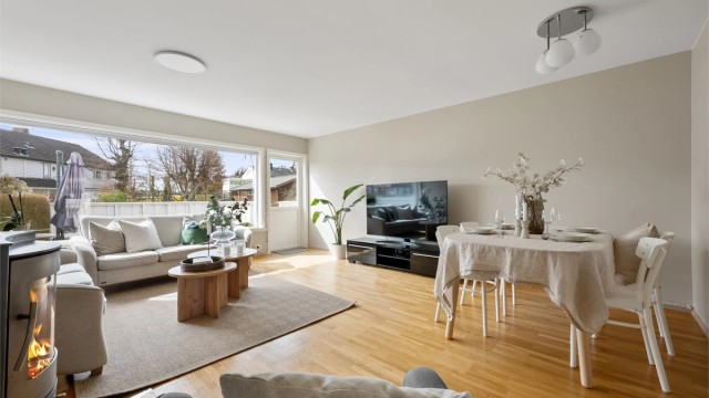 Stuen oppleves som lyst og luftig med store vindu, parkett på gulv og malte veggflater.