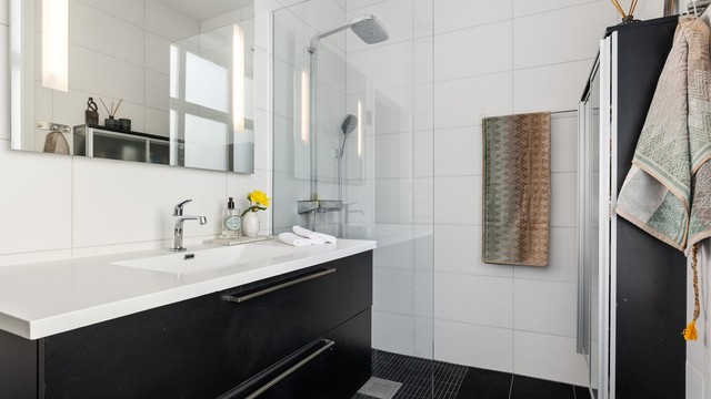 Flislagt bad med gulvvarme, innfelt belysning og et romslig dusjhjørne med glassvegg.