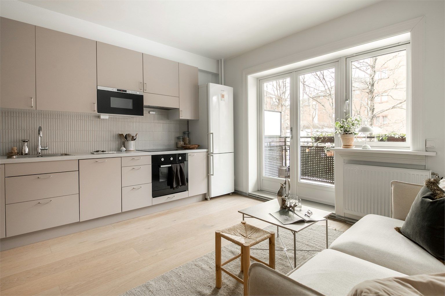 Praktisk kjøkken med glatte stilrene farger og gode materialer. Godt med skap- og benkeplass. 