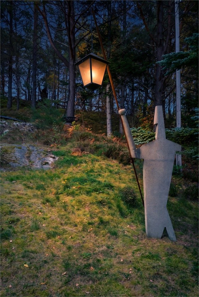 Stemningsfull belysning og skulptur i hagen mot friarealet.