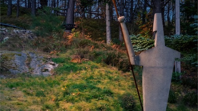 Stemningsfull belysning og skulptur i hagen mot friarealet.