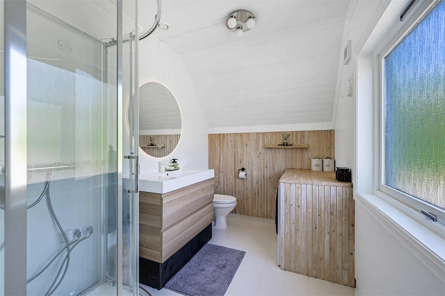 Badet ligger i tilknytning til soverommet og fremstår pent oppgradert med flislagt gulv med varmekabler, samt malt panel på vegger og i tak.