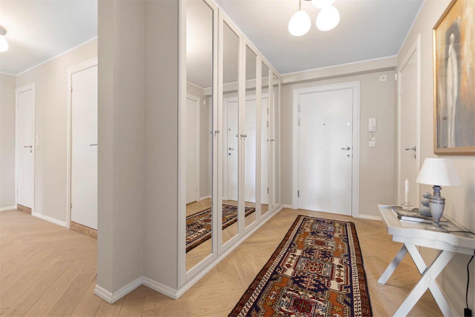 En romslig entré med en stor garderobeløsning med speilfronter. Gulvvarme gir en lun velkomst.