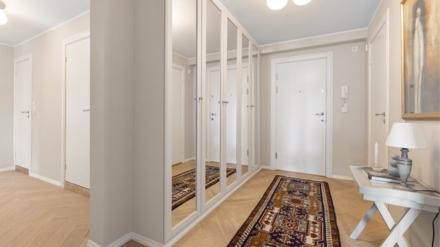 En romslig entré med en stor garderobeløsning med speilfronter. Gulvvarme gir en lun velkomst.