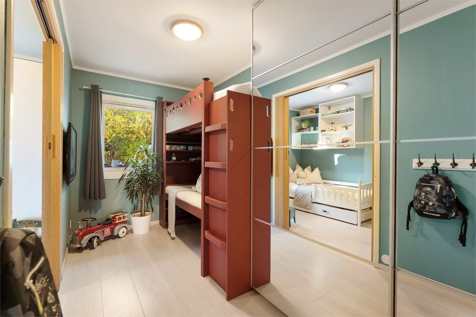 Stor skyvegarderobe og plassbygget køyeseng/høyseng med sofa under.